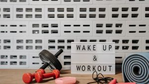 Fitness gear and motivational sign in home gym setup against a brick wall.